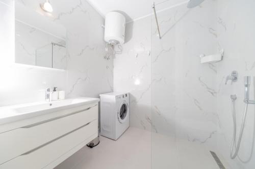 a white bathroom with a sink and a washing machine at La barca apartments in Becici