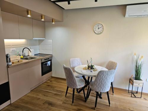 a kitchen with a table and chairs and a clock on the wall at PREMIUM APARTMAN ELENI ROOMS,oaza mira i tisine u centru Vrnjacke banje in Vrnjačka Banja