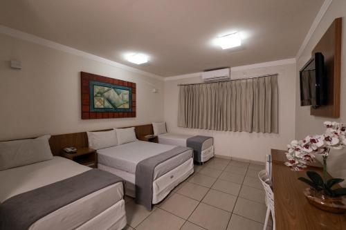 um quarto de hotel com duas camas e uma televisão em Havana Express em Uberaba