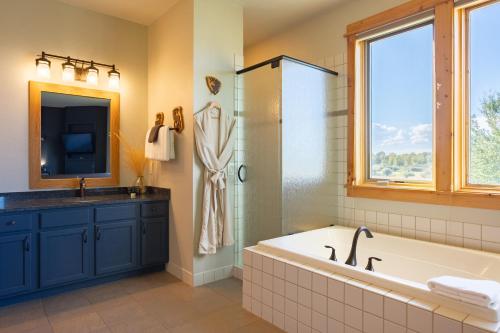 a bathroom with a tub and a sink and a television at Gallatin River Lodge in Bozeman