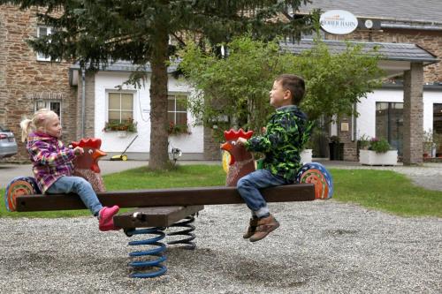 two children sitting on a wooden bench on a playground at Sonnenhotel Hoher Hahn in Schwarzenberg