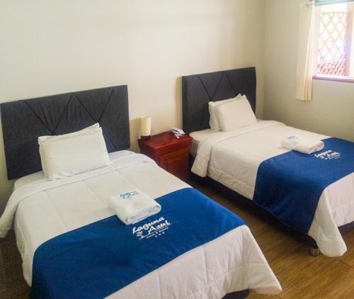 a room with two beds with blue and white sheets at Hotel Laguna Azul in Sauce