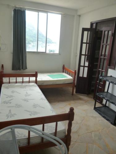 a room with a bed and a window and a bed and a table at Farol do cais in Niterói
