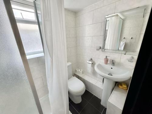 a white bathroom with a toilet and a sink at Private London Apartment in London