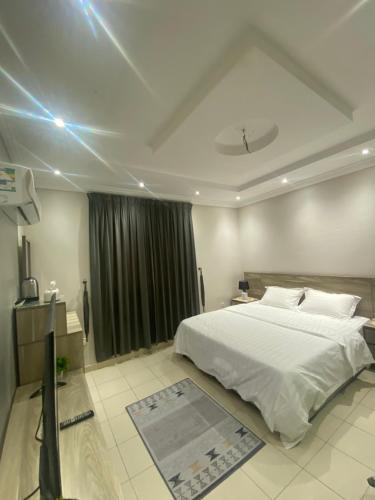 een slaapkamer met een groot wit bed en een televisie bij شقة مفروشة in Jeddah