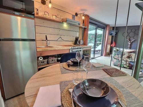 una cocina con una mesa de madera con copas de vino. en Les Cabanes de Koad'dour - séjour SPA dans les arbres, en Les Portes du Coglais