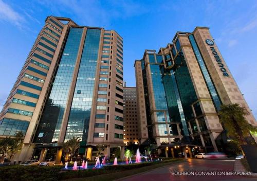 two tall buildings with a fountain in front of them at FLAT HOTEL DOIS QUARTOS AV IBIRAPUERA 2927 in Sao Paulo