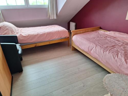 two beds in a room with purple walls and wooden floors at Kapstertje in Grimbergen