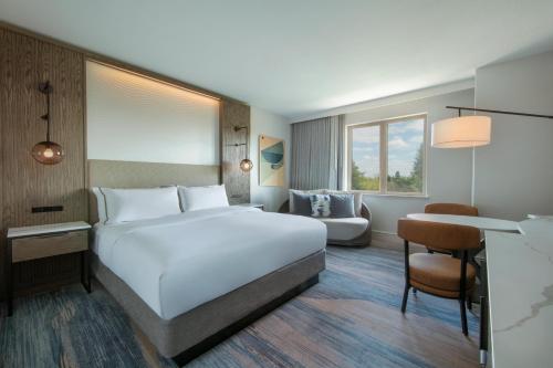 a bedroom with a large white bed and a couch at The Westin Sacramento Riverfront Hotel & Spa in Sacramento