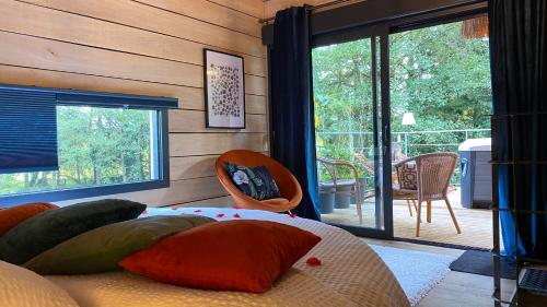 a bedroom with a bed with pillows and a balcony at Les Cabanes de Koad'dour - séjour SPA dans les arbres in Les Portes du Coglais