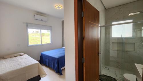 a bedroom with a bed and a glass shower at Casa aconchegante perto do Clube Marina in Palmeiras
