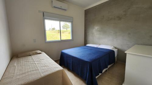 a bedroom with a blue bed and a window at Casa aconchegante perto do Clube Marina in Palmeiras
