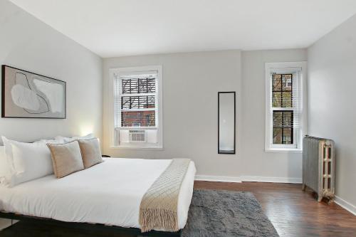 um quarto branco com uma cama grande e 2 janelas em 1BR Tranquil Hyde Park Apartment - Harper 202 & 402 rep em Chicago