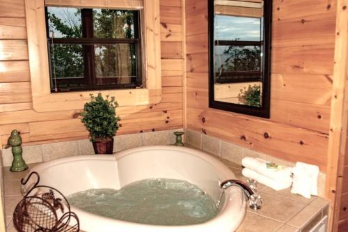 a tub in a log cabin bathroom with windows at Hideaway Haven in Waldens Creek