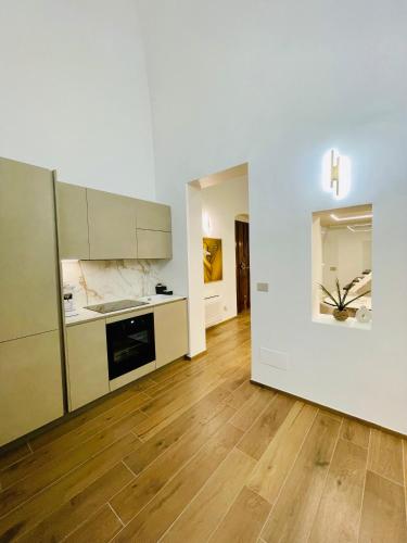 a kitchen with white cabinets and a wooden floor at Suite169 Gold in Bari