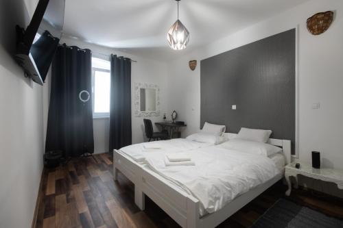 Un dormitorio con una gran cama blanca y un televisor. en Maria Q. Cantoni, en Zadar