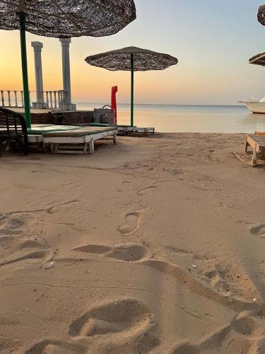 a beach with umbrellas and footprints in the sand at Al mashrabiya apartment 2 bed room in Hurghada