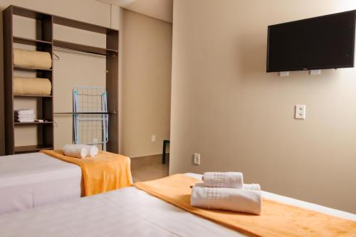 a room with two beds and a flat screen tv at Vila Castelo Residencial no Centro de Foz in Foz do Iguaçu