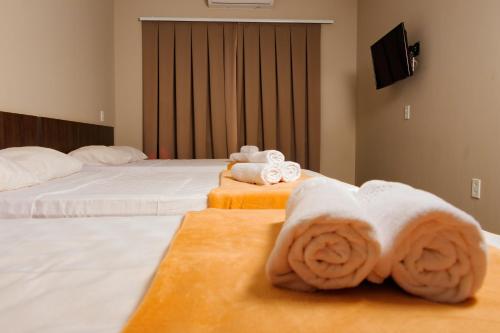 a hotel room with two beds with towels at Vila Castelo Residencial no Centro de Foz in Foz do Iguaçu