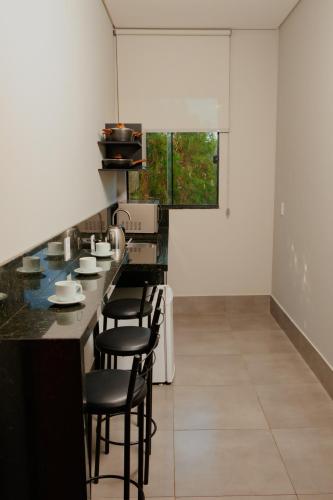 a kitchen with a counter with stools at Vila Castelo Residencial no Centro de Foz in Foz do Iguaçu