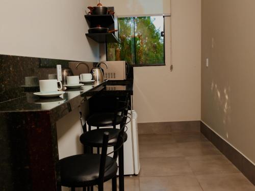 a kitchen with a counter and stools in a room at Vila Castelo Residencial no Centro de Foz in Foz do Iguaçu