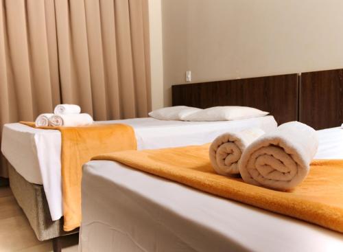 a hotel room with two beds with towels at Vila Castelo Residencial no Centro de Foz in Foz do Iguaçu