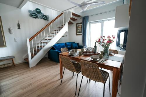 une salle à manger avec une table, des chaises et un escalier dans l'établissement Apartament Morze, Sarbinowo, à Sarbinowo