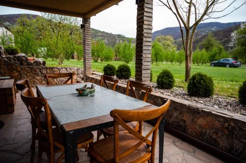 a table and chairs on a patio with a view of a field at Dedin Drinski Dom in Bajina Bašta
