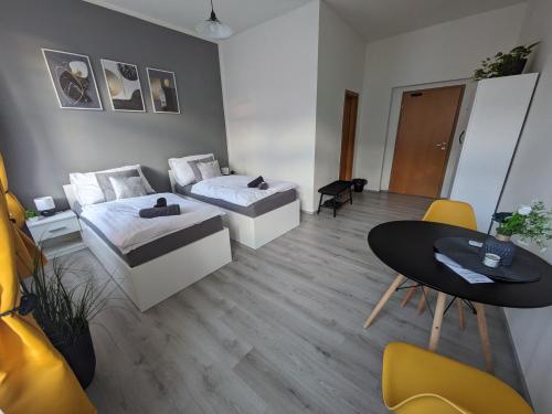 ニンブルクにあるPenzion Grand Nymburkのベッド2台、テーブル、椅子が備わる客室です。