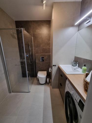 uma casa de banho com um chuveiro, um WC e um lavatório. em Apartament Topolowa 48 em Elblag