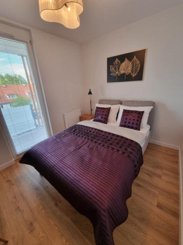 a large bed in a bedroom with a large window at Apartament Topolowa 48 in Elblag