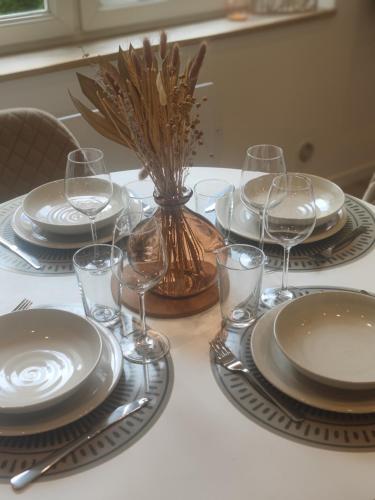 une table avec des assiettes et des verres à vin dessus dans l'établissement Villa Leone 2, à Dunkerque