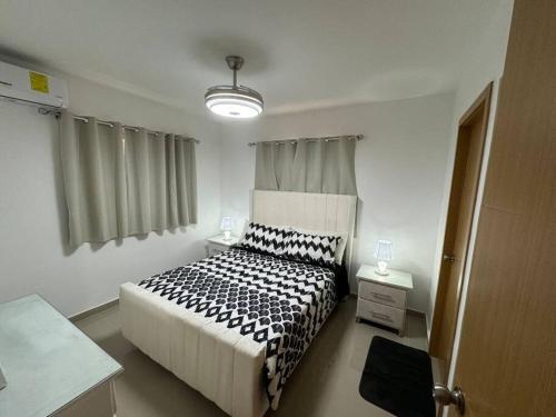 a bedroom with a bed with a black and white comforter at Apartamento nuevo con wi-Fi, gimnasio, parqueo in Peralejo