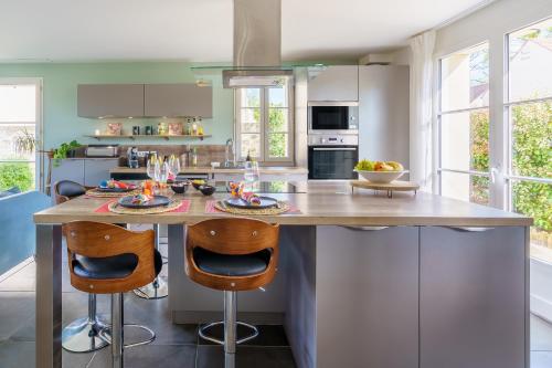une cuisine avec un grand îlot et deux tabourets de bar dans l'établissement Le Pavillon Émeraude - Jardin - Parking privé privé - Proche Chantilly & Parc Astérix - Kids Friendly jeux babyfoot tram-poline - RER D Direct Paris, à Coye-la-Forêt