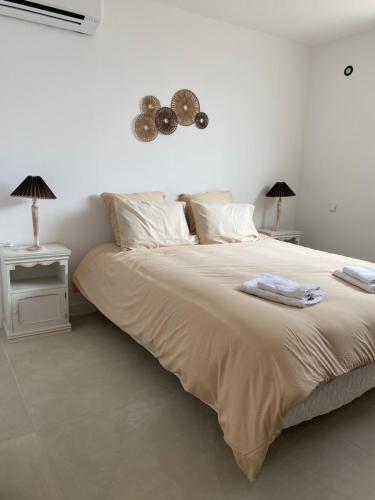 - une chambre blanche avec un grand lit et 2 tables dans l'établissement Gîtes chez Marceau, à Rasteau