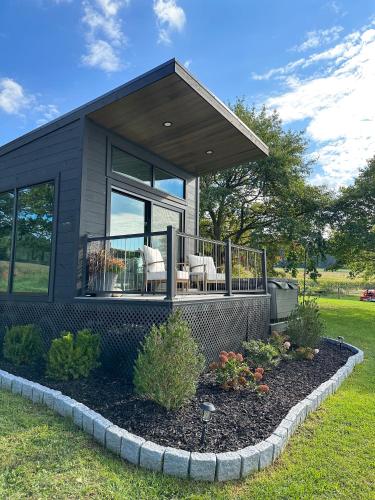 una pequeña casa negra con porche y algunas plantas en Modern Tiny Home, 