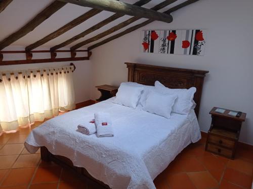 una camera da letto con un letto bianco e due pantofole sopra di Casa Hotel La Villa del Rosario a Villa de Leyva