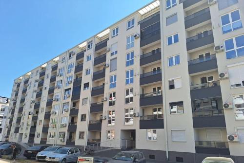 un gran edificio de apartamentos con coches aparcados en un aparcamiento en MINT Apartment, en Skopje