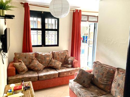 a living room with a couch and red curtains at OKRA HOUSE in Entebbe