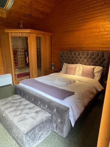 a large bed with a bench in a room at The Snug - Luxury En-suite Cabin with Sauna in Grays Thurrock in Grays Thurrock