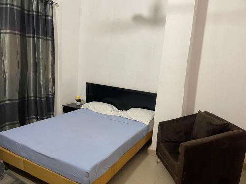 a small bedroom with a bed and a chair at Appartement Studio Damou in Bamako