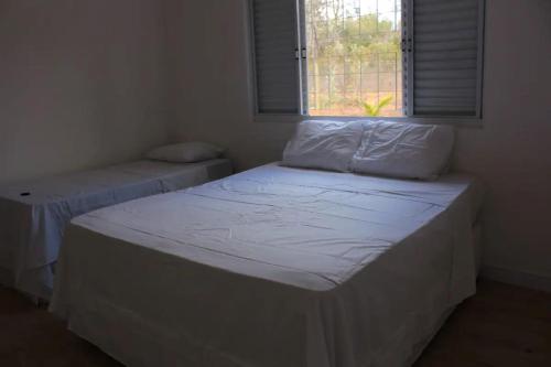 two beds in a room with a window at Casa na fazenda inteira ou quartos individuais no Hostel Recanto da Felicidade Paraopeba in Paraopeba