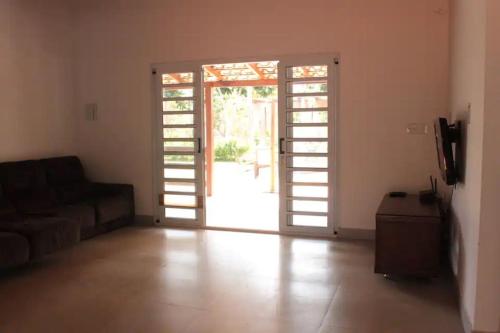 a living room with a couch and an open door at Casa na fazenda inteira ou quartos individuais no Hostel Recanto da Felicidade Paraopeba in Paraopeba