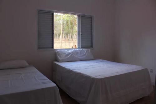 - 2 lits dans une chambre avec fenêtre dans l'établissement Chacara Alto Padrão Recanto Felicidade Paraopeba, à Paraopeba