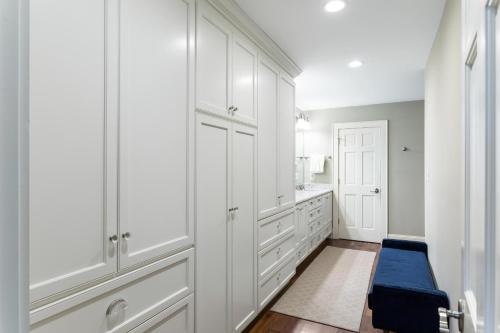 a white kitchen with white cabinets and a blue bench at 3554 Seascape Oceanfront Villa in Kiawah Island