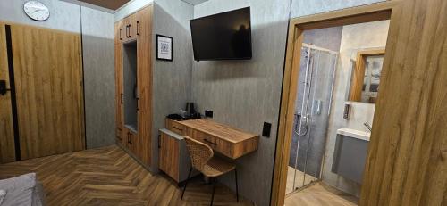 uma pequena casa de banho com um lavatório e uma televisão na parede em Przy Młynówce 24h self check in em Głogówek