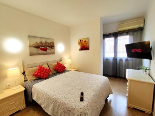 1 dormitorio con 1 cama con almohadas rojas y TV en Tranquilo apartamento con vistas al mar. en Puerto de Alcúdia