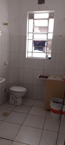 baño con aseo y lavabo y ventana en Rafa's hostel en São Paulo
