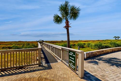 a wooden boardwalk with a palm tree and a sign at Ocean One in Hilton Head Island