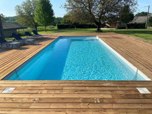 une piscine avec une terrasse en bois et une visière de piscine dans l'établissement Lodge Nature à Vigeois, à Vigeois
